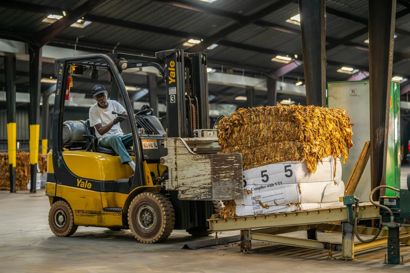 Real industry photograph of a forklift operator moving a pallet inside a warehouse